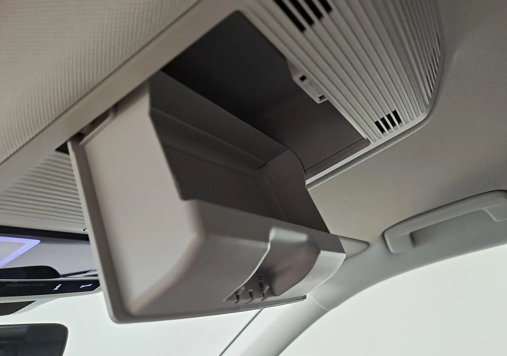 Gros plan sur le rangement lunettes ouvert fixé au plafond intérieur du Volkswagen Tiguan 2025 couleur Argent Dolomite.