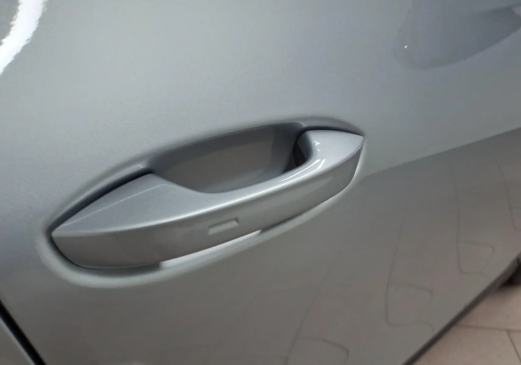 Gros plan sur la poignée de porte côté gauche du Volkswagen Tiguan 2025 en peinture métallisée Argent Dolomite.