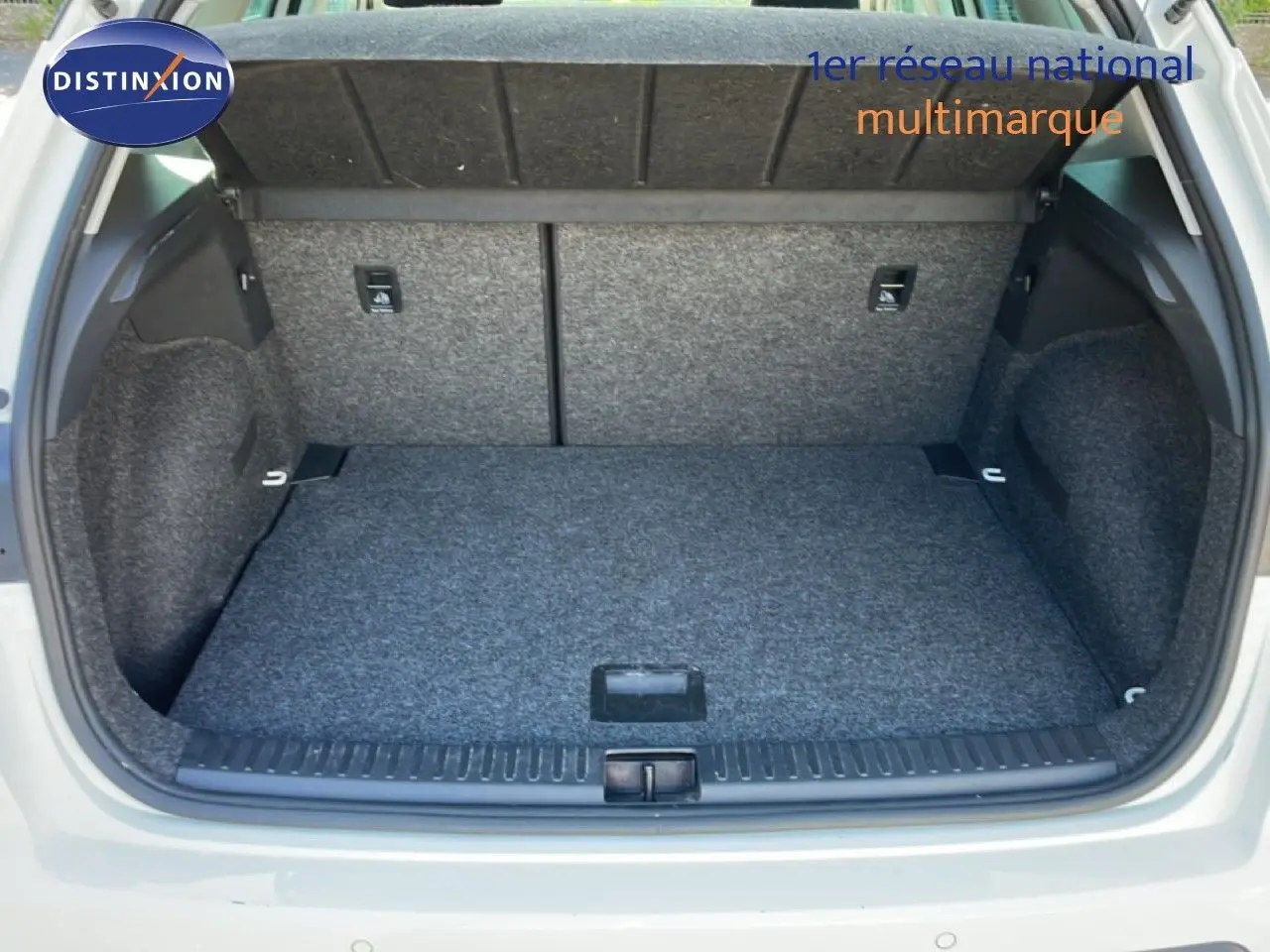 Coffre ouvert vu de l'arrière d'un SEAT Arona blanc avec toit gris, montrant l'espace de chargement vide et doublé de moquette grise.