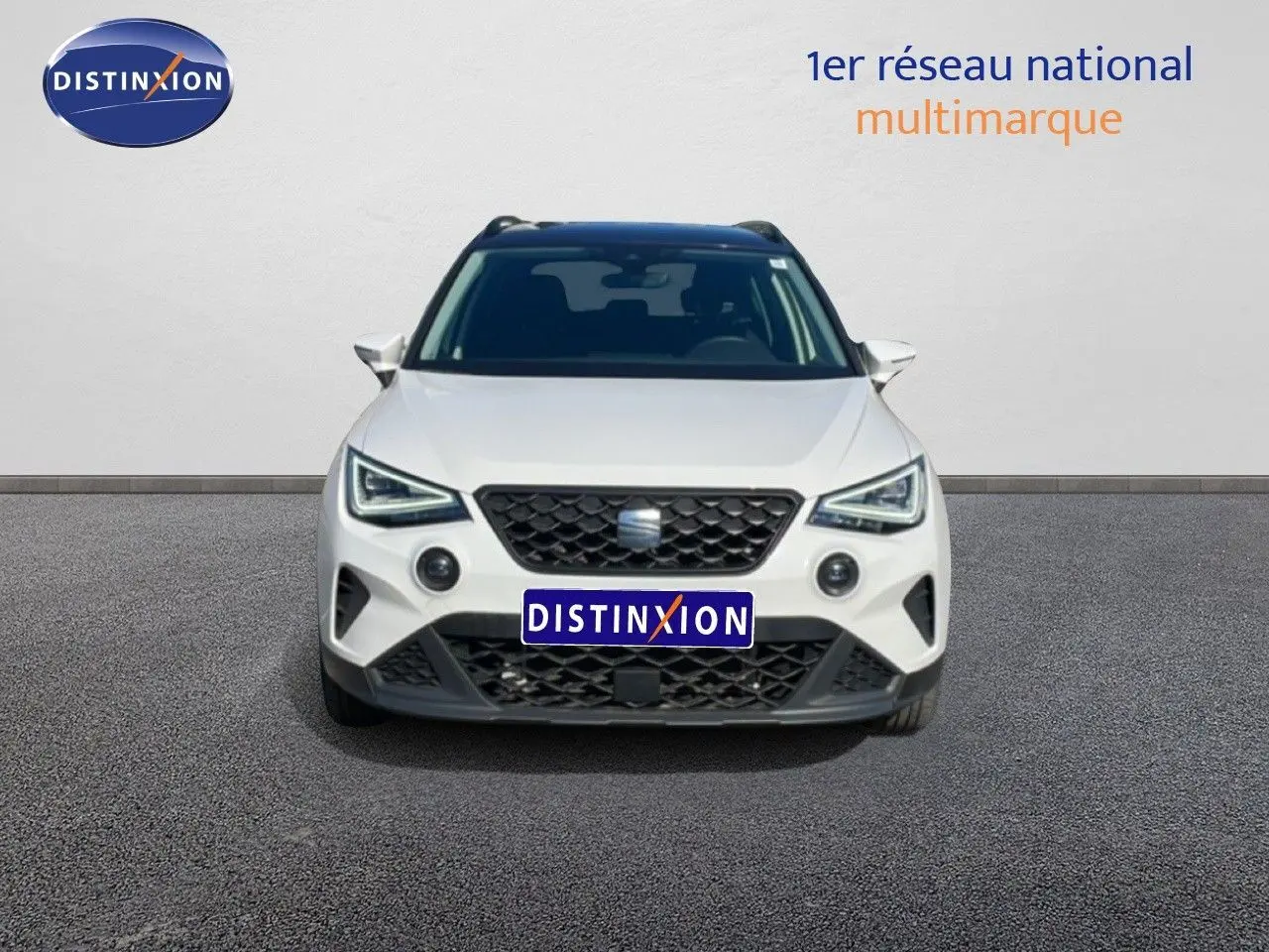 Vue avant d'un SEAT Arona blanc avec toit gris, calandre noire et feux LED distinctifs, sur fond neutre.