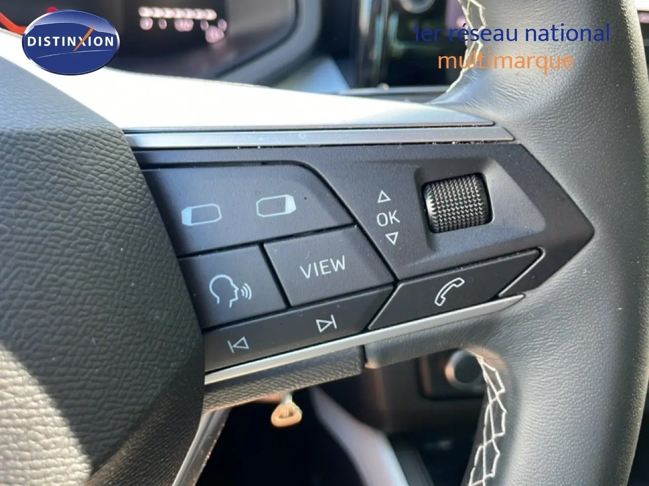 Gros plan sur les commandes gauche du volant cuir noir du SEAT Arona 2025, boutons multifonctions et molette visibles.