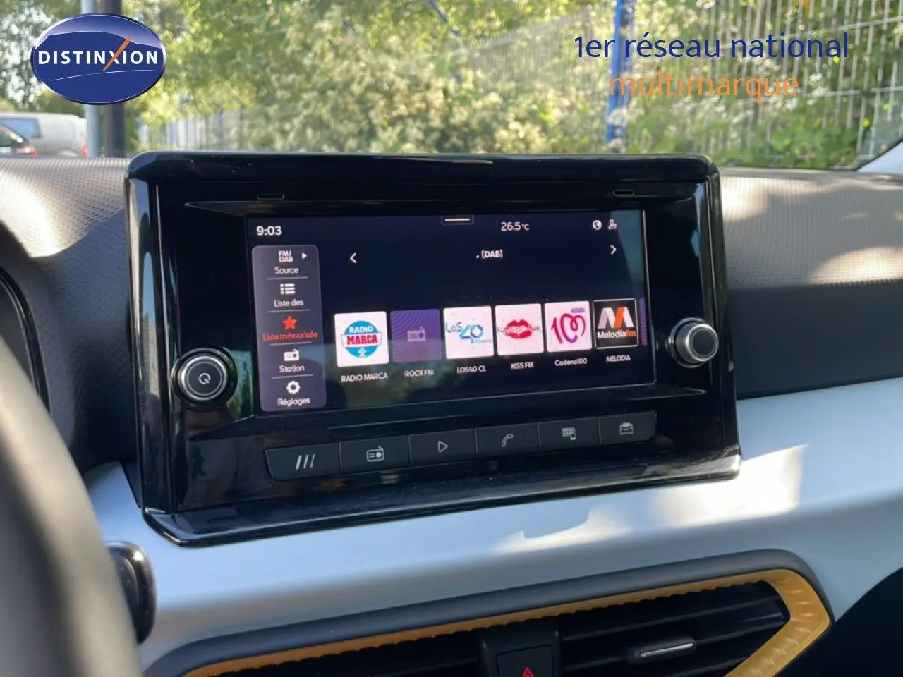 Gros plan sur l’écran tactile central du tableau de bord d’un SEAT Arona blanc avec toit gris, affichant les options radio.