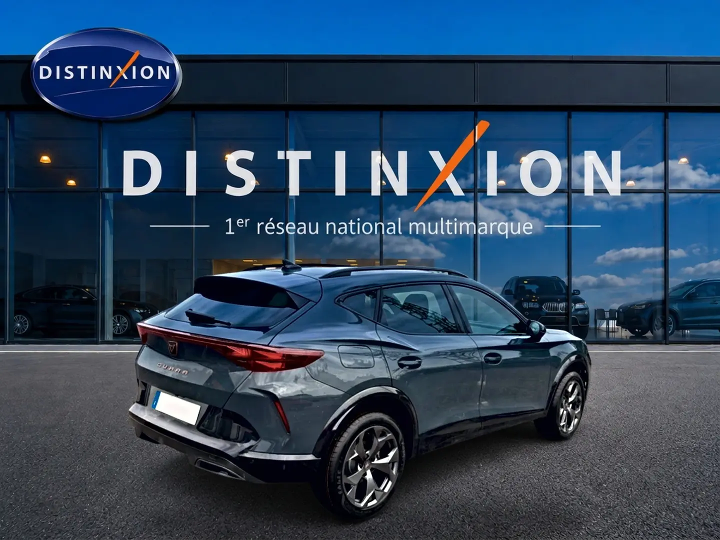 Vue 3/4 arrière droite d'une CUPRA Formentor 1.5 etsi hybrid bleu fjord avec jantes 18 pouces devant un showroom Distinxion.