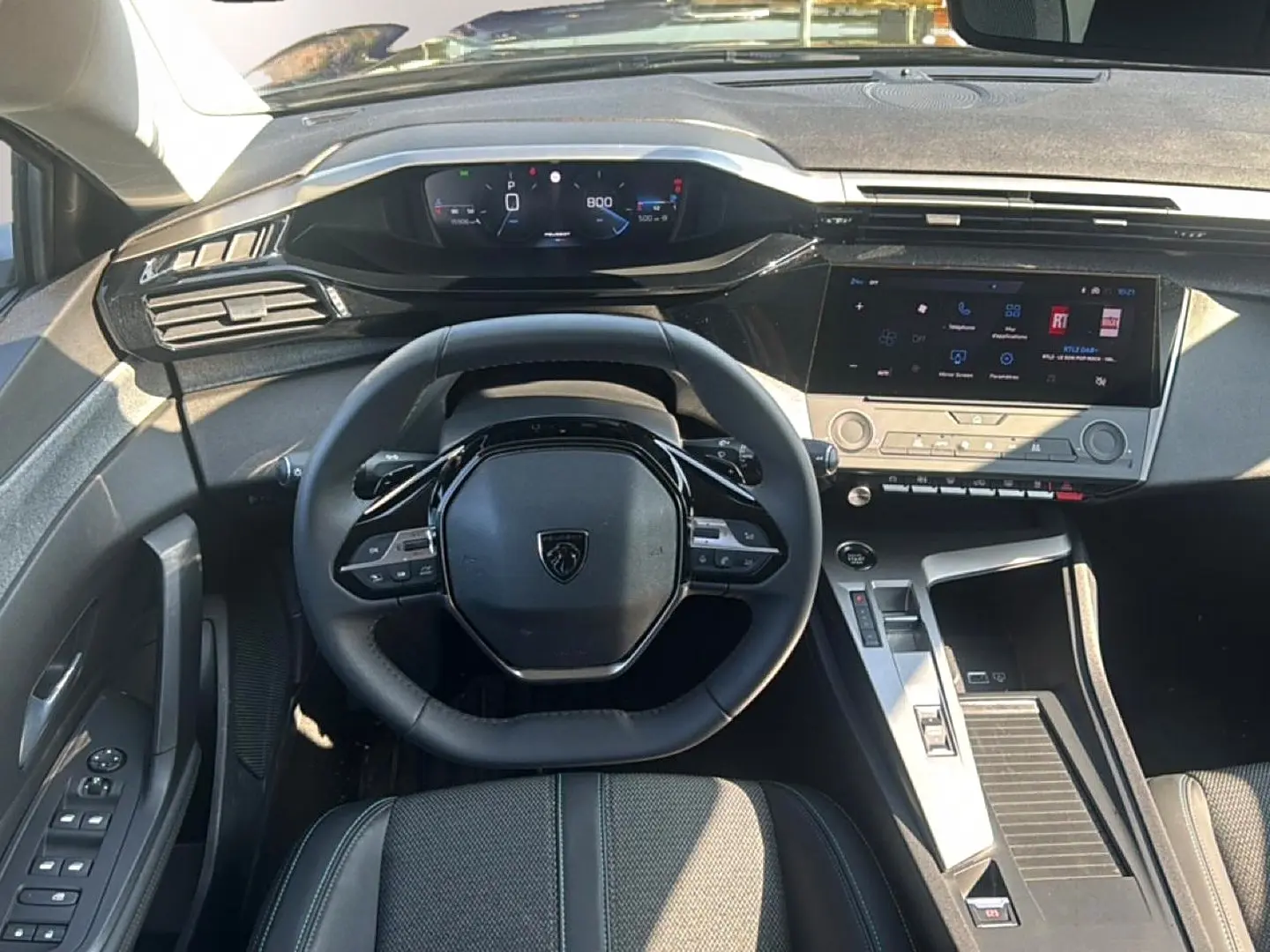 Vue intérieure frontale du tableau de bord et volant noir de la Peugeot 308 2025 avec écran tactile et affichage numérique.