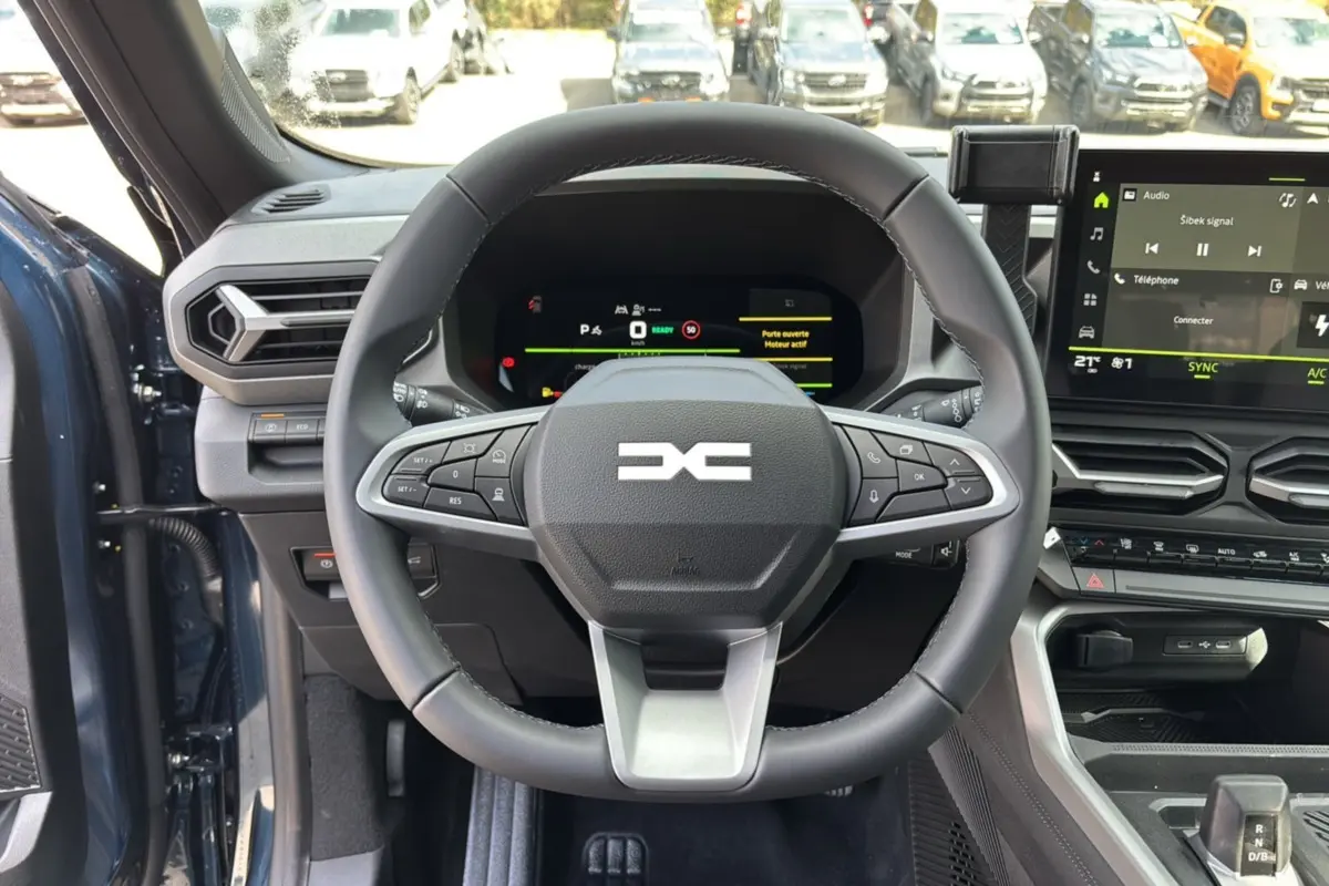 Vue intérieure centrée sur le volant cuir et le tableau de bord digital du Dacia Bigster Hybrid 155 bleu indigo.