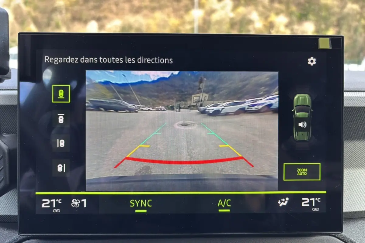 Écran multimédia montrant la caméra multiview en marche arrière du Dacia Bigster bleu indigo avec toit noir.