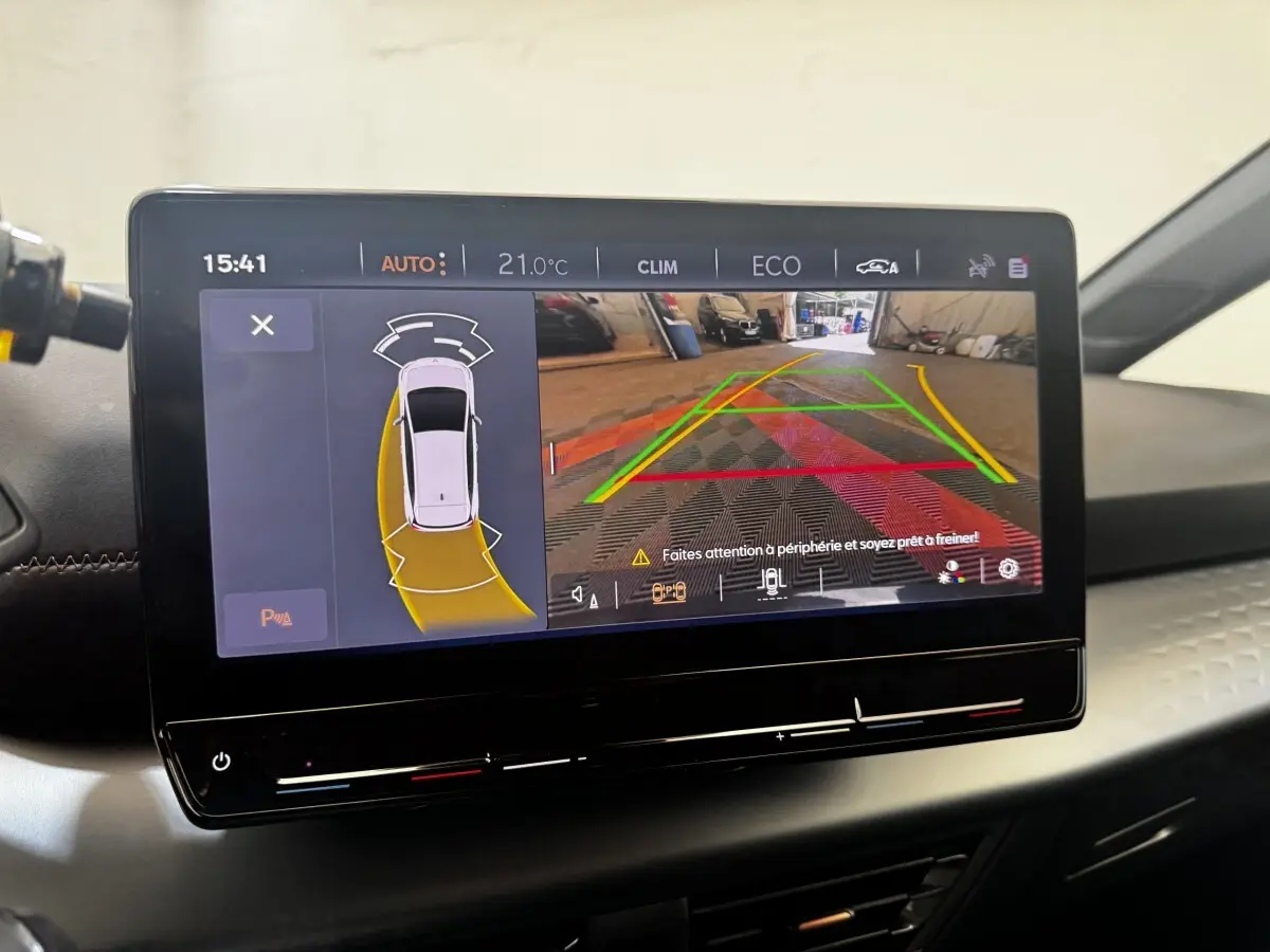 Écran tactile central du CUPRA Born 2023 montrant l’aide au stationnement avec vue caméra arrière et alertes.