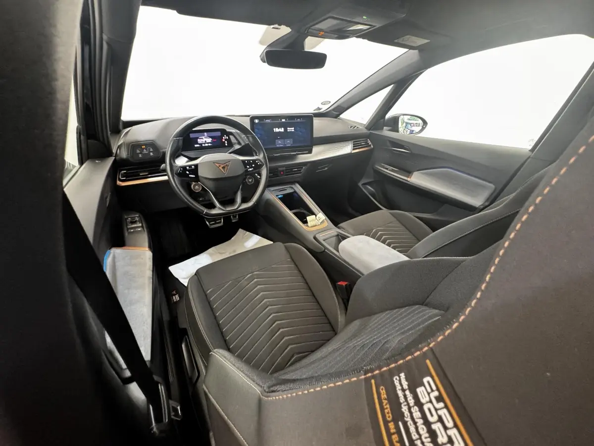 Vue intérieure avant droite du CUPRA BORN gris foncé, avec volant cuir multifonctions et écran tactile central.