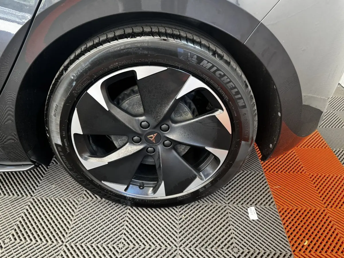 Gros plan sur la roue avant droite du CUPRA BORN gris foncé, jante noire et argent avec logo CUPRA central.