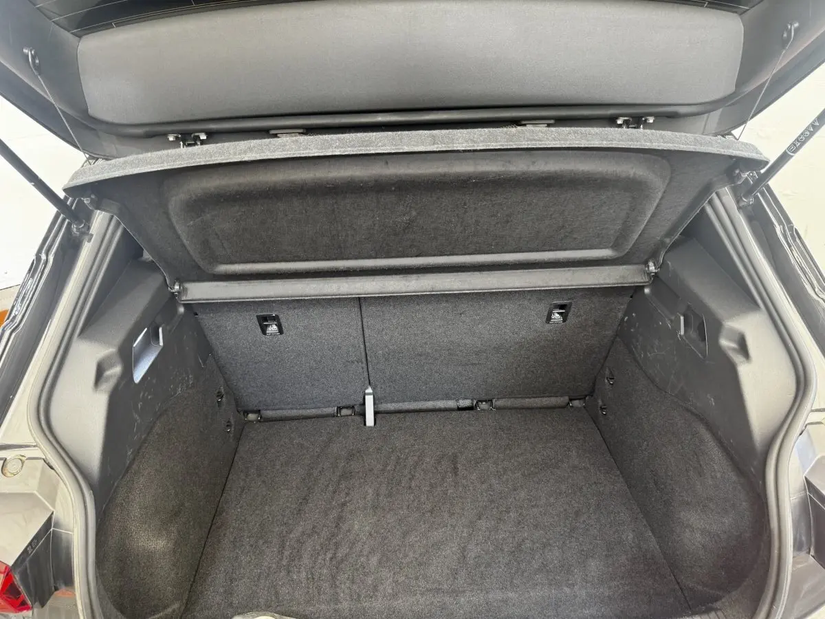 Coffre ouvert vu de l'arrière d'une CUPRA Born gris foncé, montrant l'espace de chargement et la tablette de séparation.