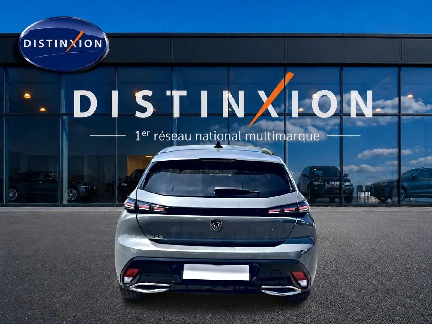 Vue arrière d'une Peugeot 308 gris 2025 garée devant une vitrine avec logo Distinxion.