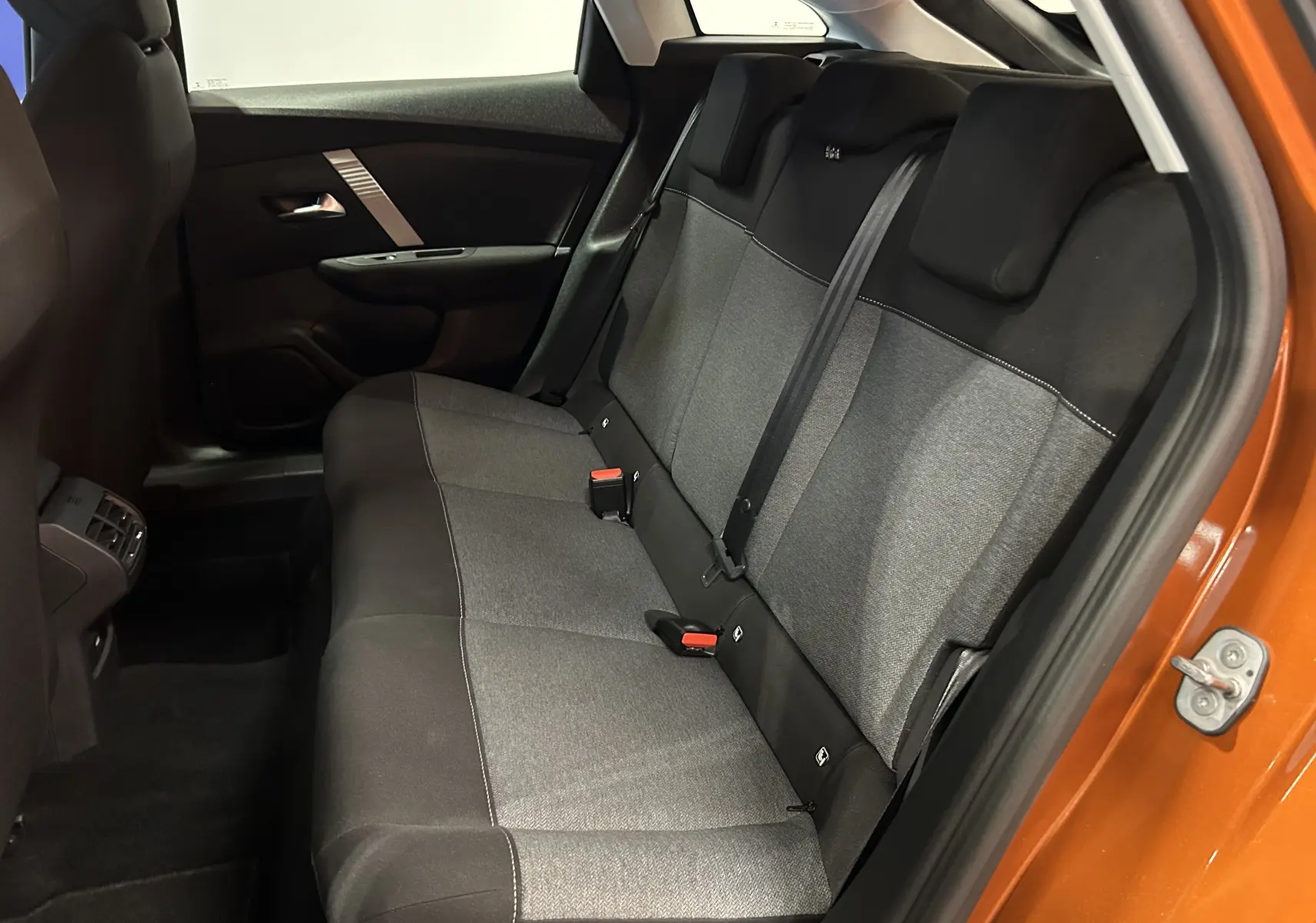 Vue intérieure côté droit des sièges arrière gris et noirs d'une Citroën C4 orange 2021 avec porte ouverte.
