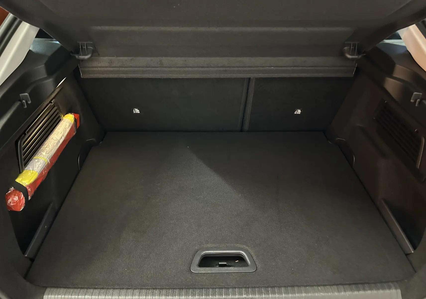 Coffre ouvert d'une Citroën C4 PureTech 100 Feel 2021, vue intérieure sur le plancher et les côtés noirs du coffre.