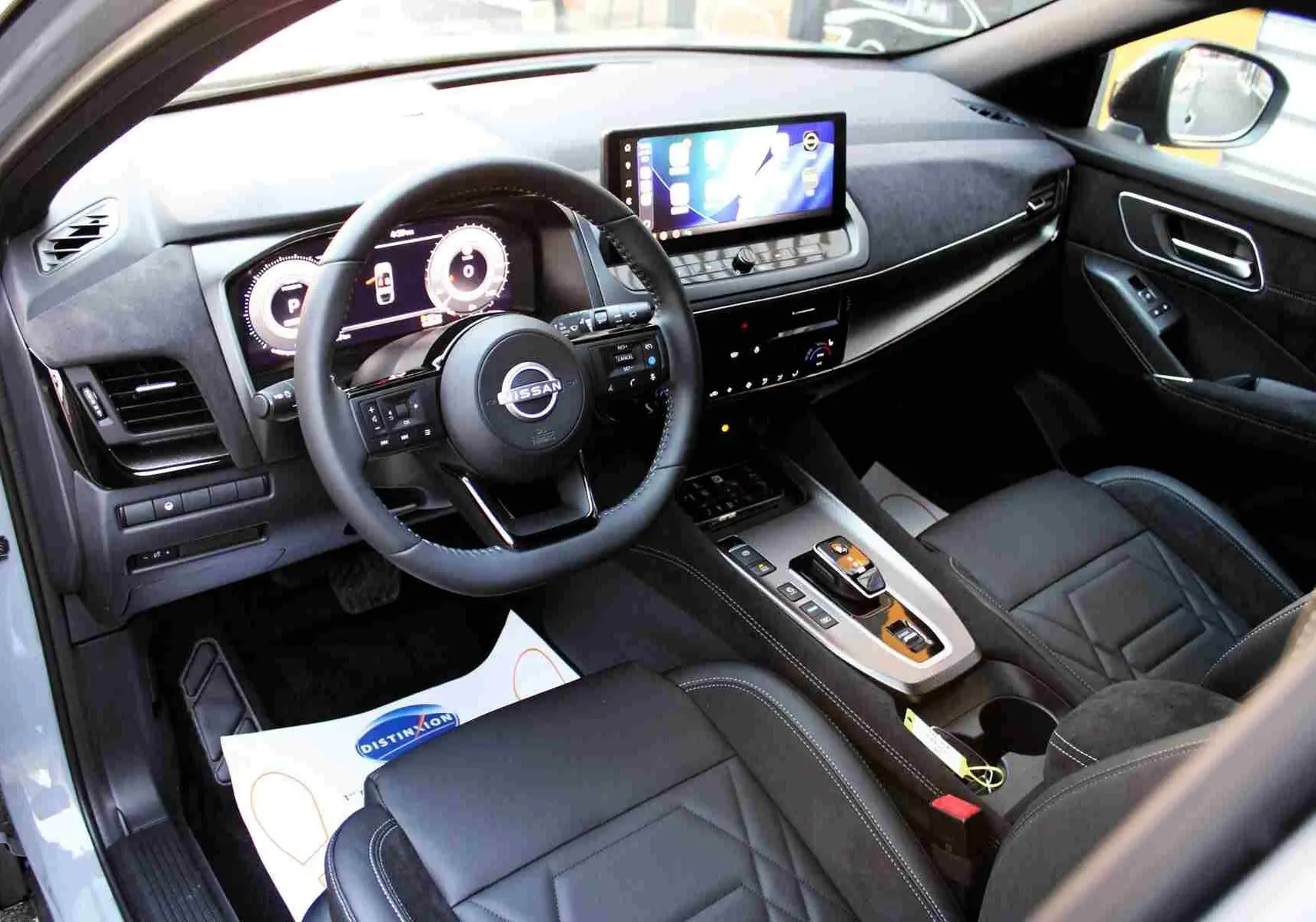 Gros plan sur la console centrale du Nissan Qashqai 2025 gris céramique, montrant les commandes de boîte auto et fonctions hybrides.