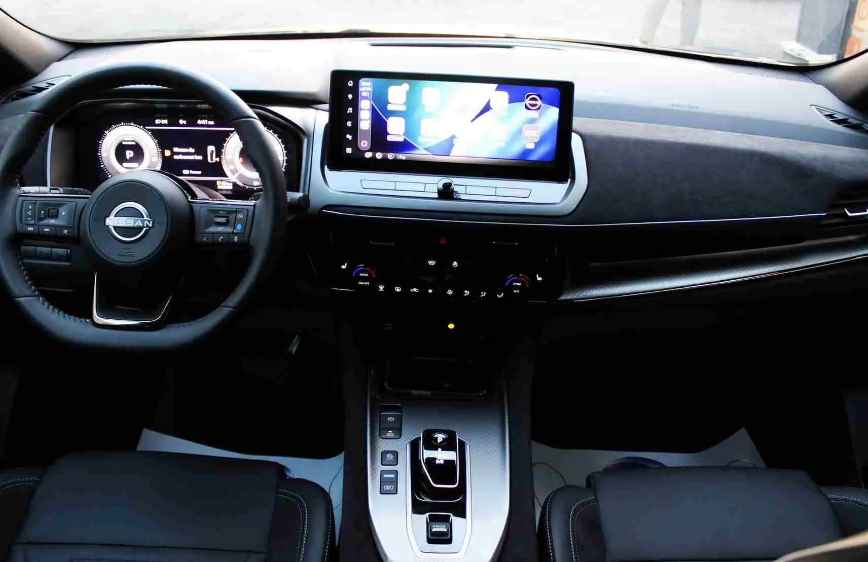 Nissan Qashqai 2025 gris céramique avec toit noir, vue 3/4 avant mettant en valeur sa calandre distinctive et ses jantes stylées.