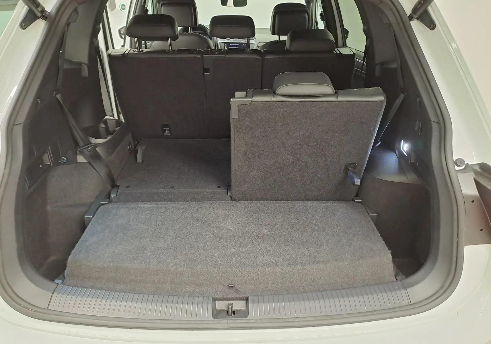 Vue arrière du coffre ouvert du Volkswagen Tiguan Allspace blanc pur 2023, montrant la banquette arrière partiellement rabattue.