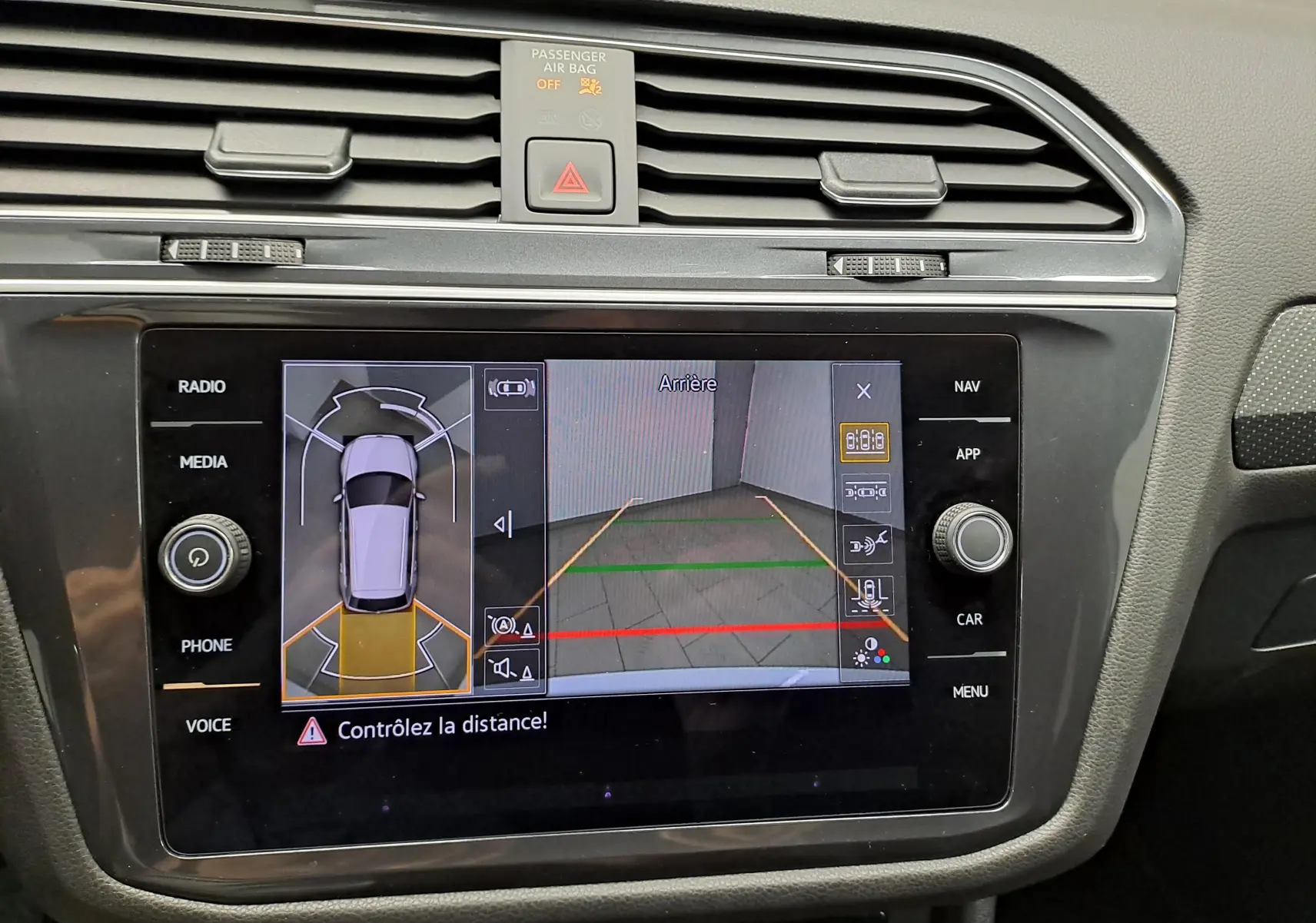 Vue rapprochée de l'écran tactile du Volkswagen Tiguan Allspace 2023 montrant la caméra de recul et les capteurs d'aide au stationnement.