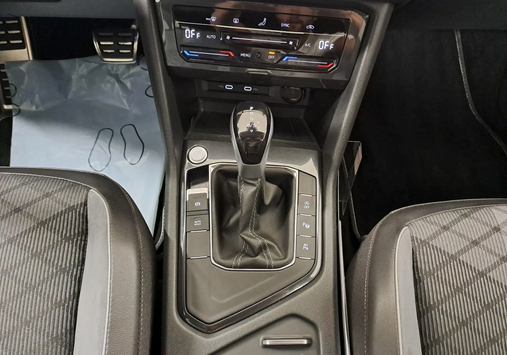 Vue plongeante sur la console centrale du Volkswagen Tiguan Allspace blanc pur 2023, avec levier de vitesse DSG7 et commandes R-Line.