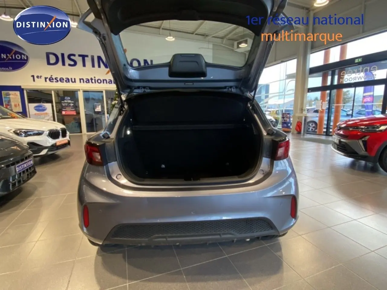 Vue arrière d'une MG3 1.5 Hybrid 2024 gris Hampstead avec coffre ouvert dans un showroom lumineux.
