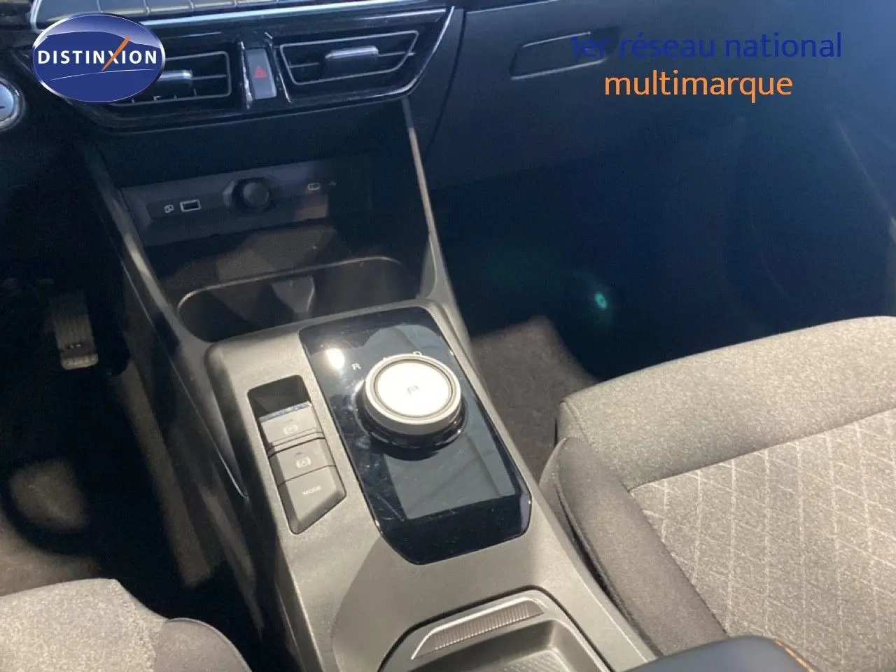 Vue rapprochée de la console centrale de la MG3 1.5 Hybrid 195ch Comfort 2024 avec molette de boîte auto et sièges tissu gris.