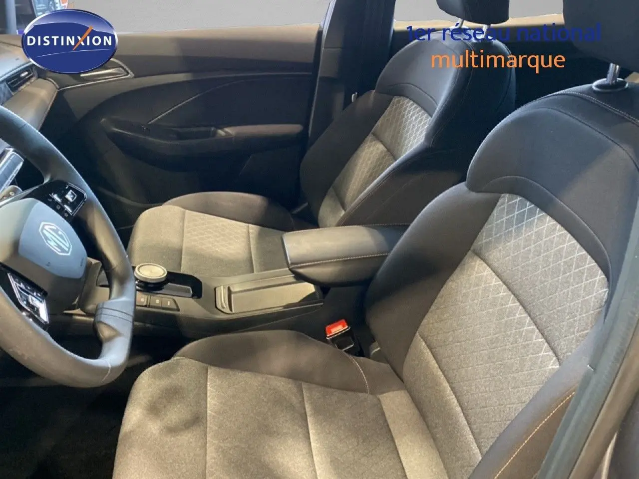Vue intérieure côté conducteur de la MG3 1.5 Hybrid 2024 avec sièges tissu gris et noir et console centrale moderne.