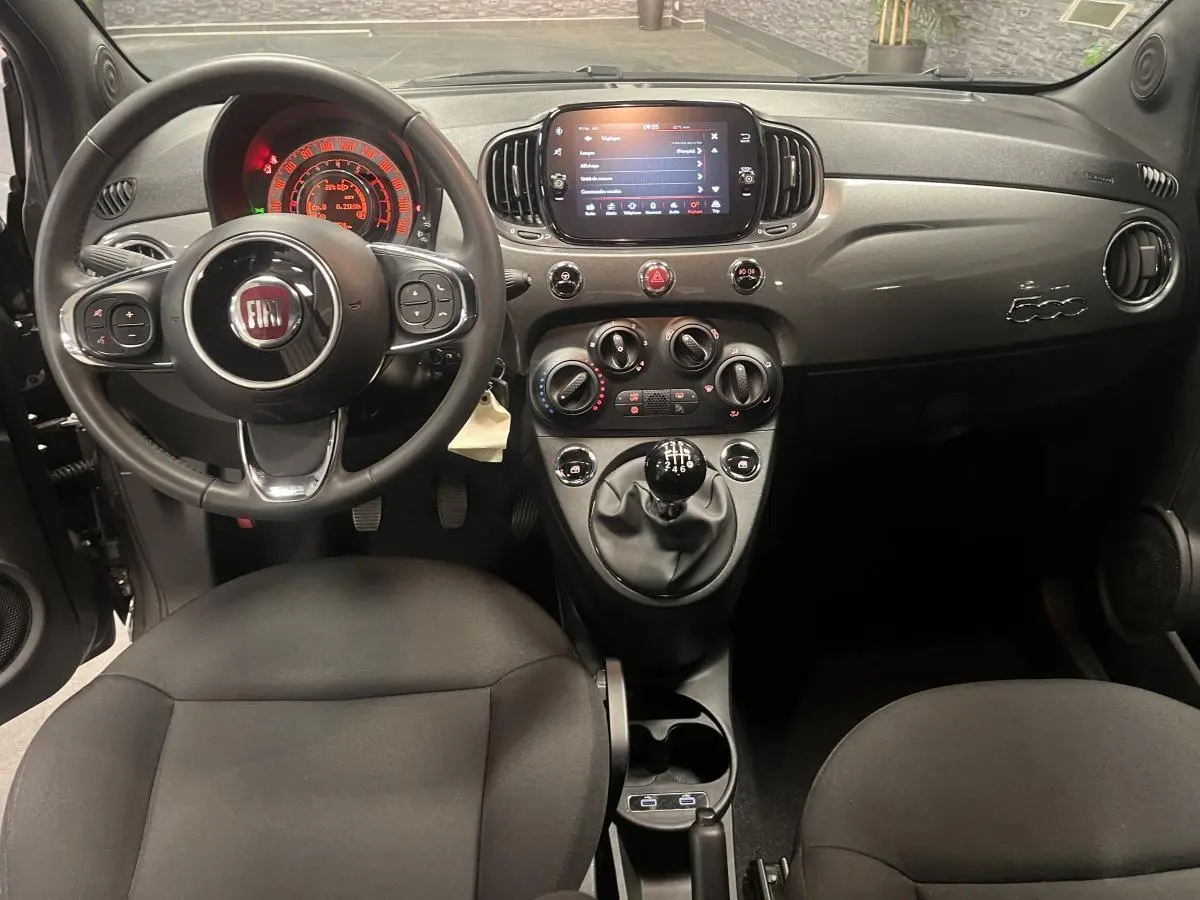 Intérieur avant de la Fiat 500 gris, tableau de bord avec écran tactile et volant noir en éco-cuir.