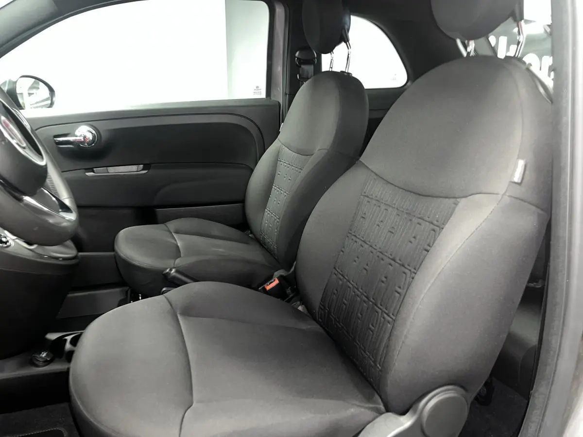 Vue intérieure côté gauche montrant les sièges avant en tissu noir avec monogramme FIAT sur la Fiat 500 gris 2023.
