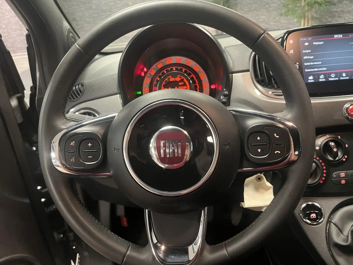 Vue rapprochée du volant noir en éco-cuir de la Fiat 500 gris, avec tableau de bord et commandes visibles.
