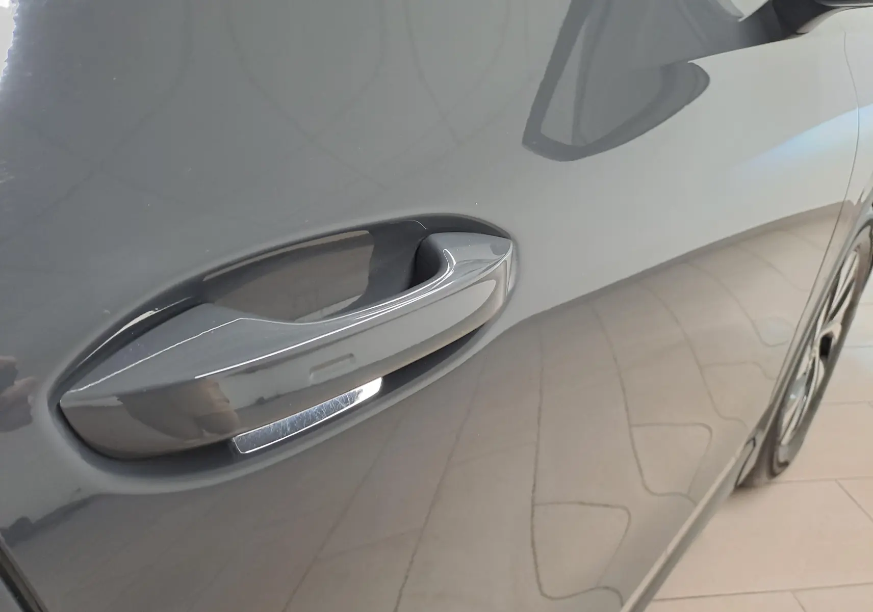 Poignée de porte côté gauche du Volkswagen Tiguan 2024 gris Urano, vue rapprochée sur la carrosserie lisse.