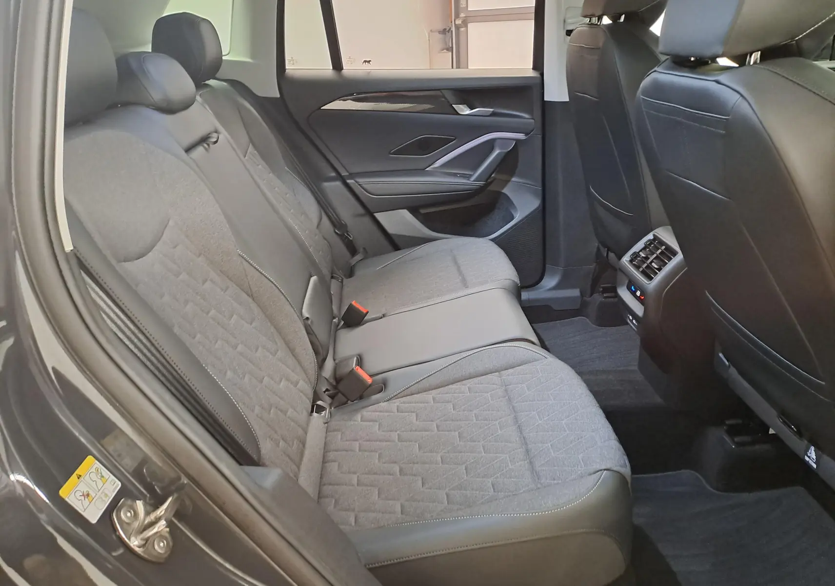 Vue intérieure côté gauche des sièges arrière gris du Volkswagen Tiguan 2024 avec finitions tissu et cuir.