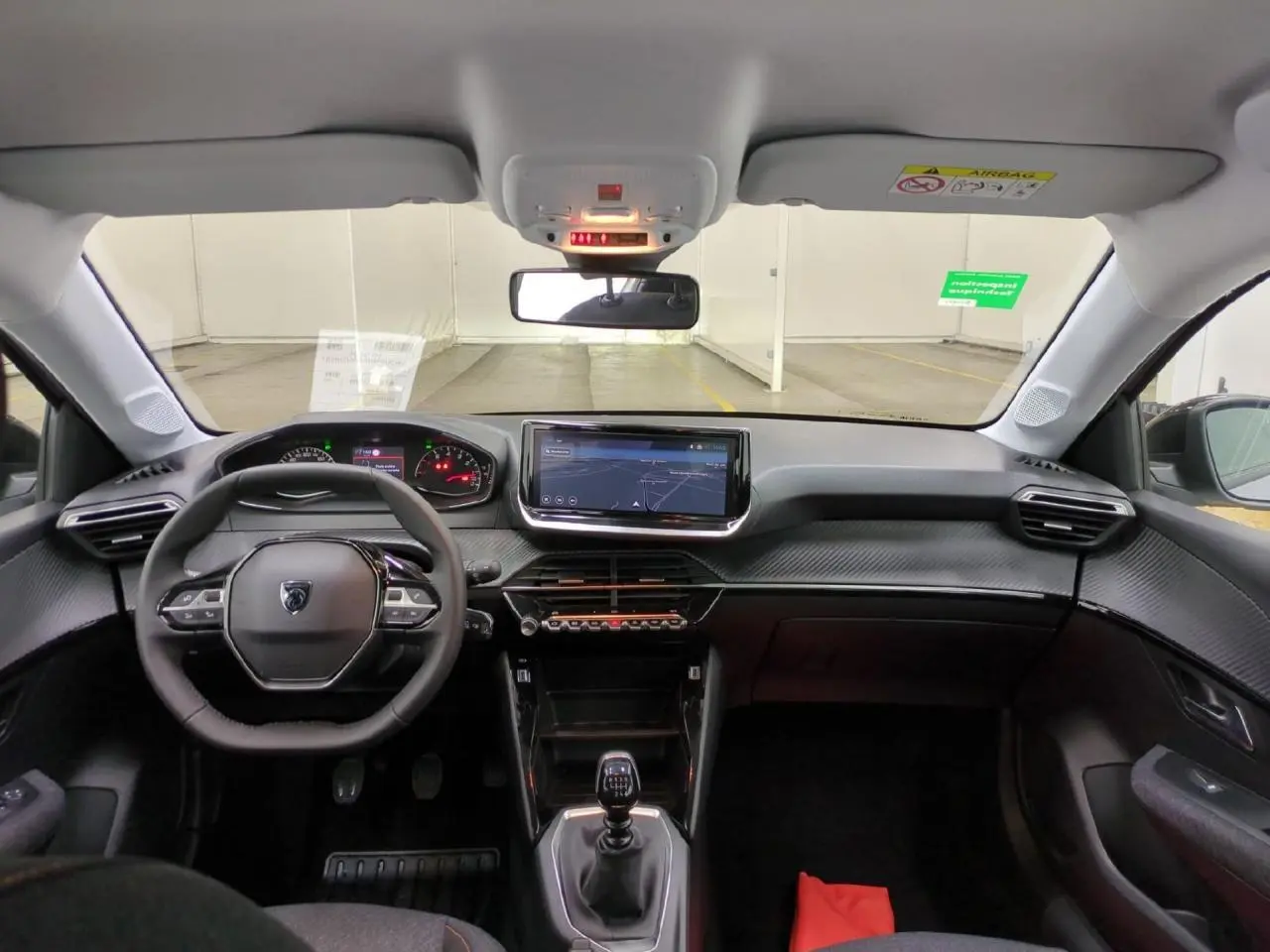 Vue intérieure avant du Peugeot 208 gris clair 2025 avec tableau de bord carbone et écran tactile 10 pouces.