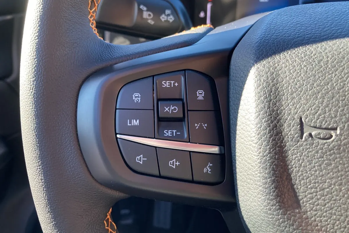 Gros plan sur les commandes multifonctions à gauche du volant cuir du Ford Ranger Wildtrak blanc glacier 2025.