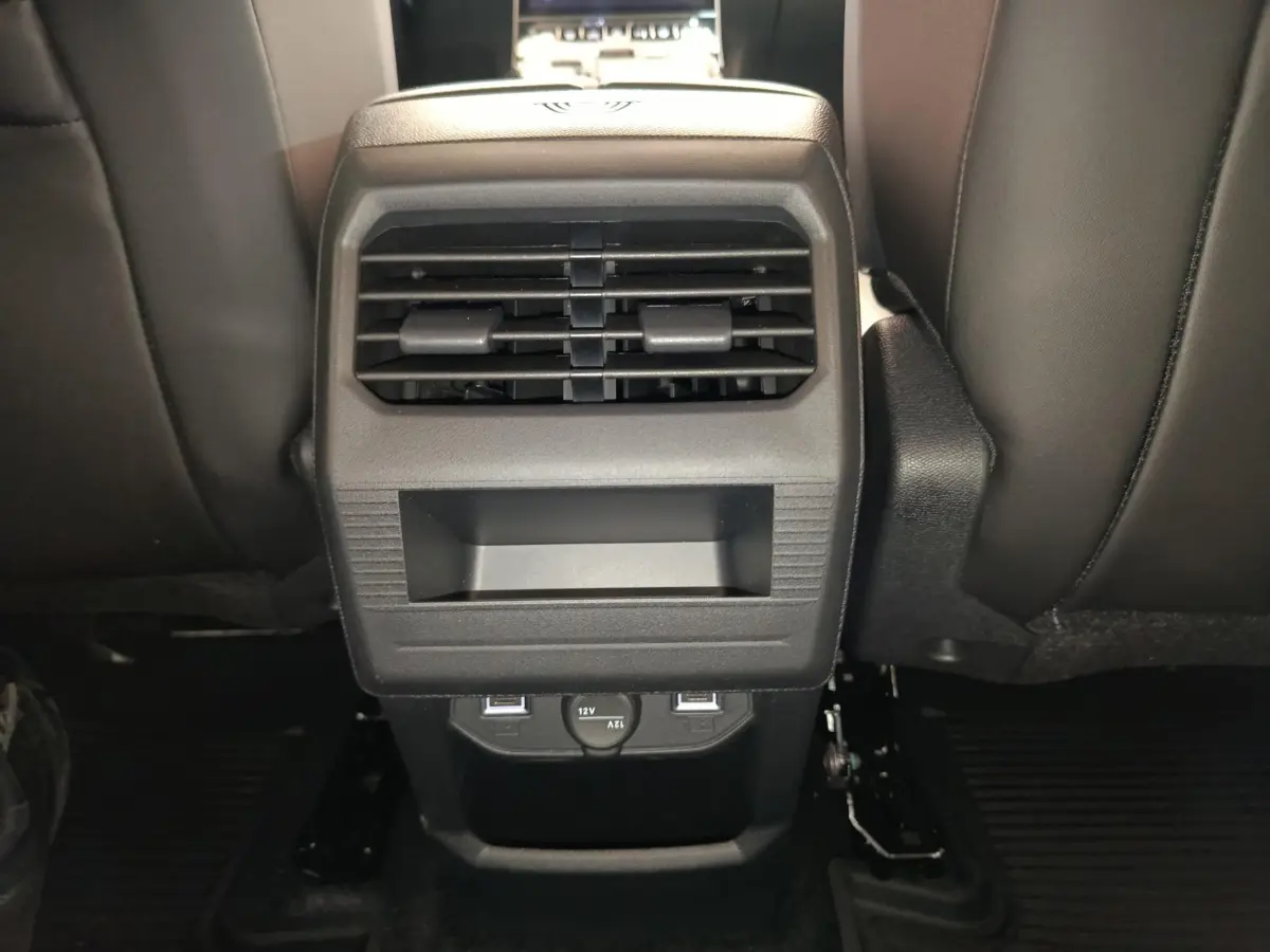 Vue rapprochée de la console centrale arrière noire du Citroën C5 Hybride 2025 avec bouches d’aération et prises USB.