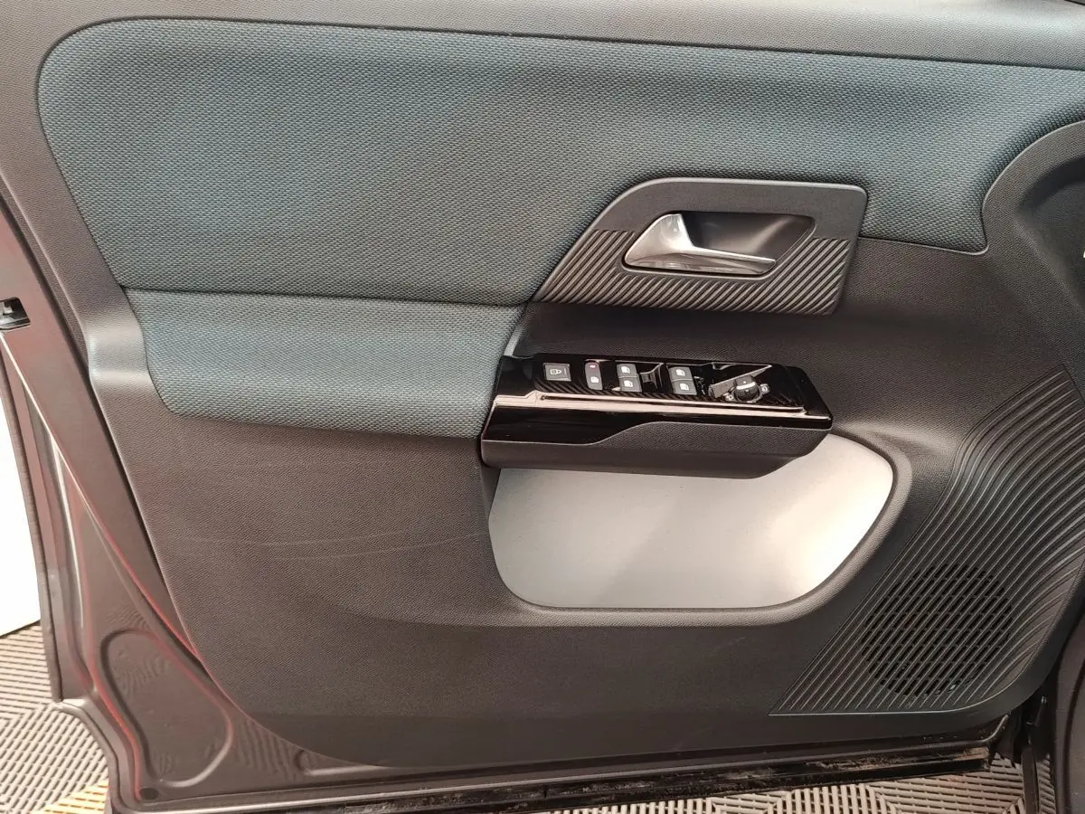 Détail de la porte côté conducteur de la Citroën C5 hybride 2025, avec commandes électriques et finition bicolore grise.