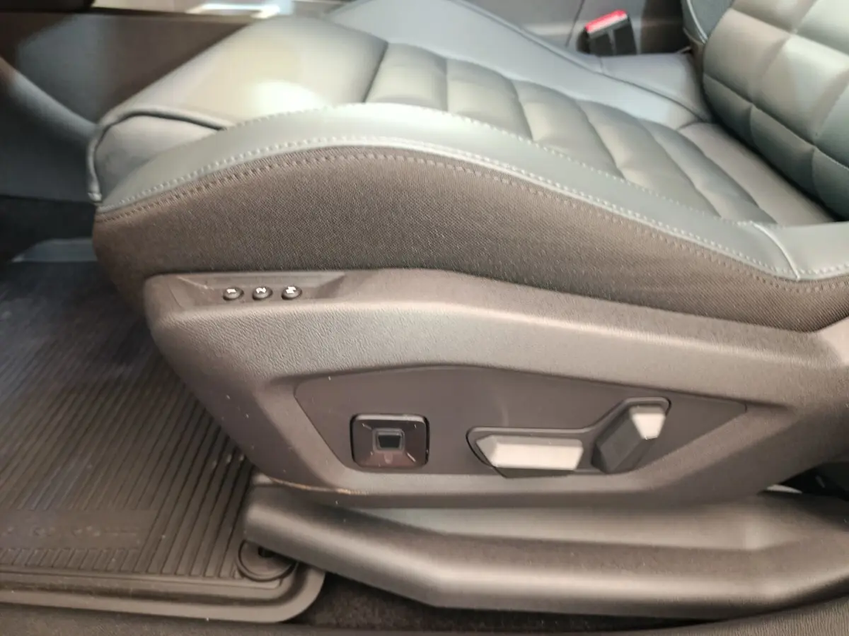 Gros plan sur les commandes de réglage électrique du siège avant droit en cuir gris foncé de la Citroën C5 hybride 2025.