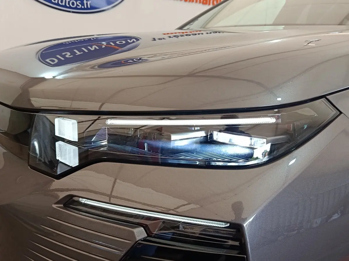 Gros plan sur le phare avant droit LED d'une Citroën C5 hybride gris foncé, soulignant les lignes modernes du capot.