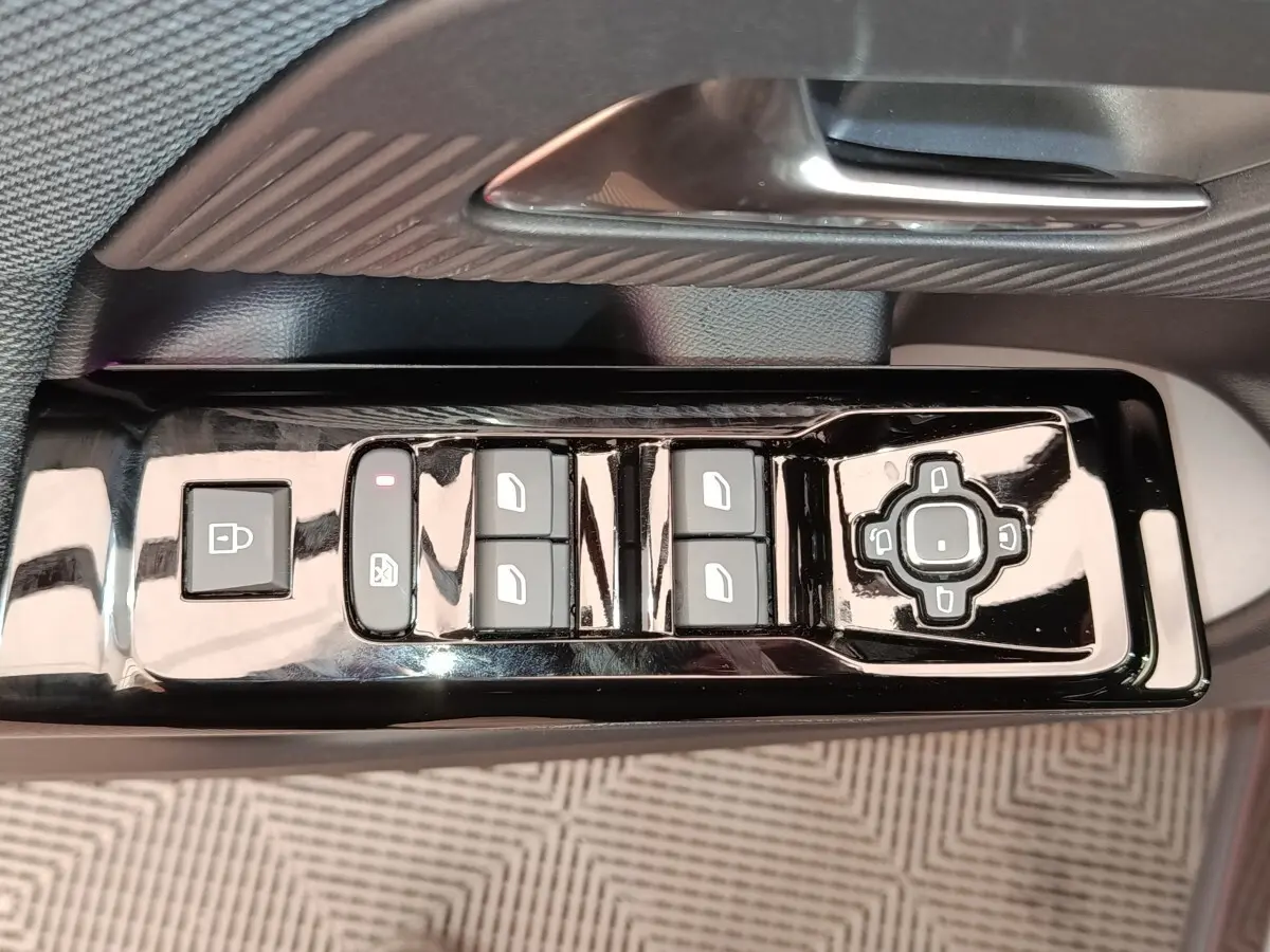 Gros plan sur la commande de lève-vitres et réglage des rétroviseurs côté conducteur d'une Citroën C5 hybride gris foncé.