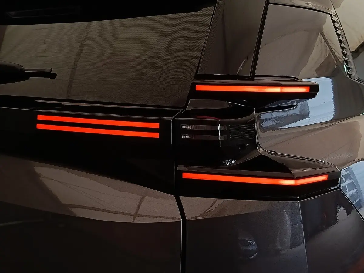 Feux arrière allumés en rouge sur la partie gauche d'une Citroën C5 hybride gris foncé, vue en gros plan.