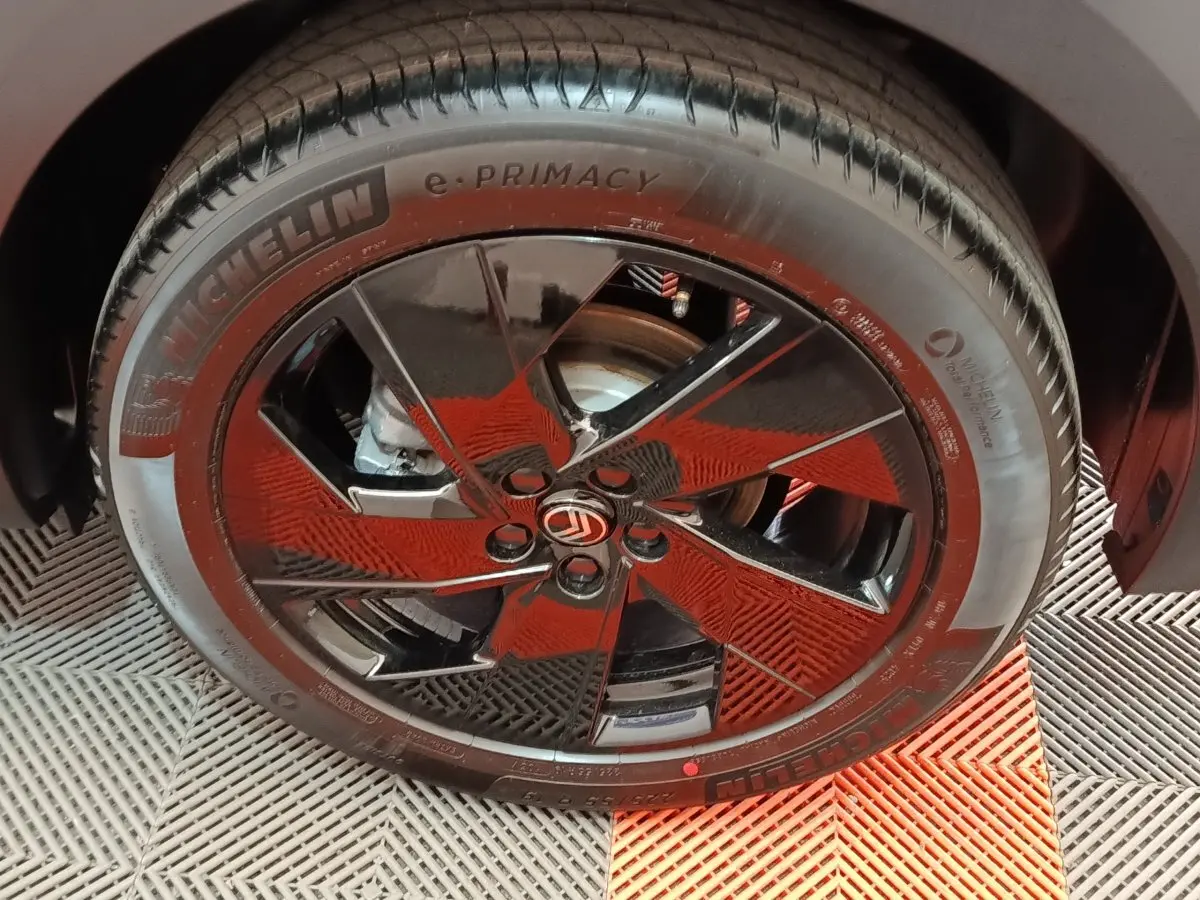 Gros plan sur la roue avant droite d'une Citroën C5 gris foncé avec jante noire brillante et logo Citroën central.