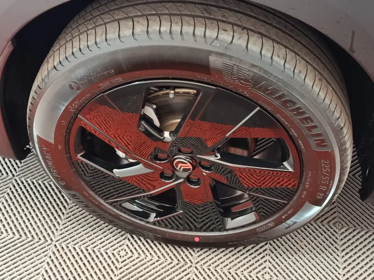 Gros plan sur la roue avant droite avec jante noire brillante et pneu Michelin sur Citroën C5 gris foncé.