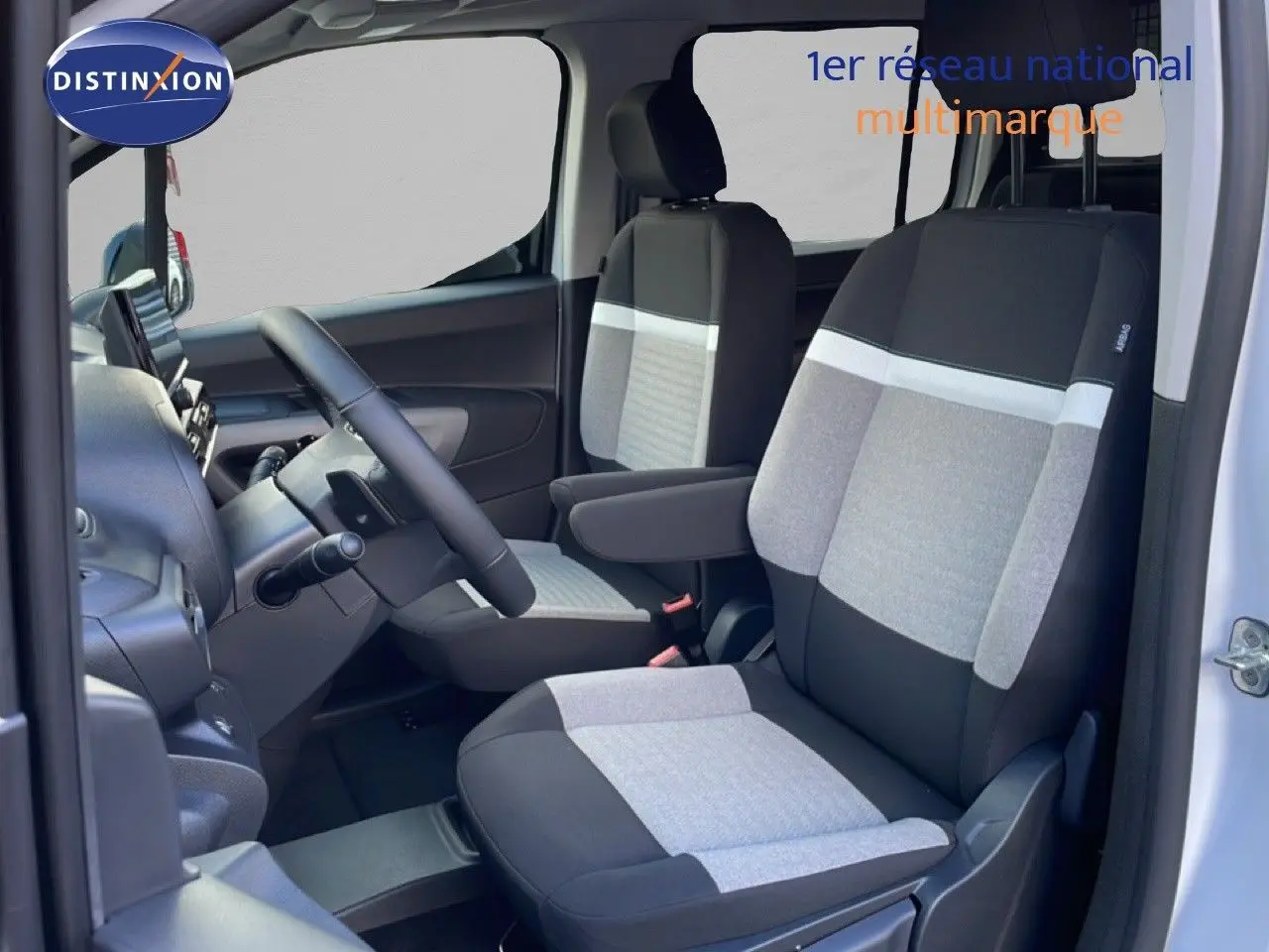 Vue intérieure côté conducteur du Citroën Berlingo Multispace 2025, sièges tissu bicolore gris et noir, volant multifonction.