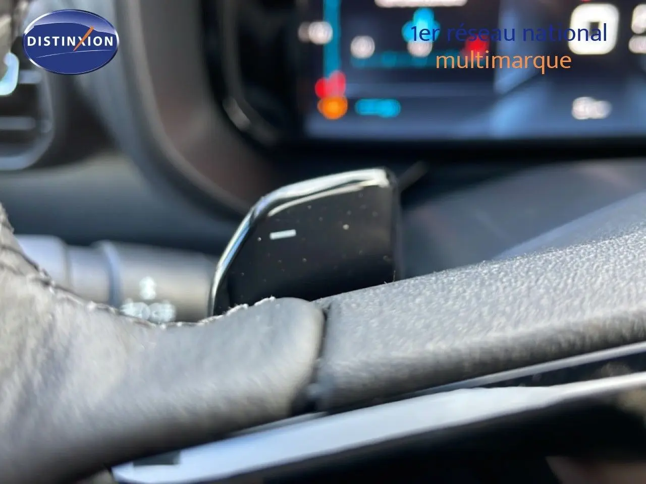Gros plan sur la commande au volant en cuir noir du Citroën Berlingo Multispace 2025, intérieur moderne avec écran tactile flou.