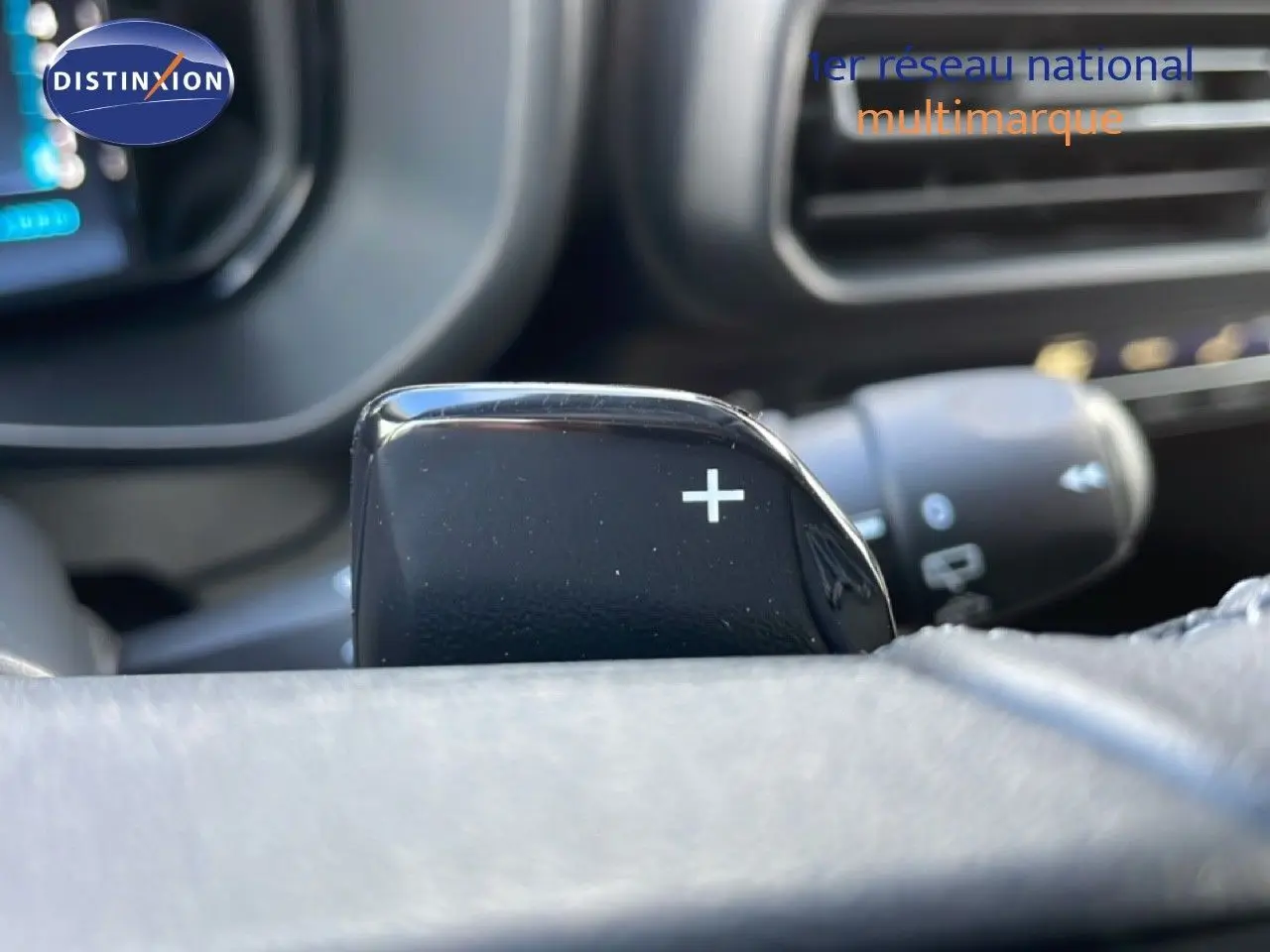 Gros plan sur la palette de changement de vitesse "+" côté droit du volant dans l'habitacle noir du Citroën Berlingo blanc glacier 2025.