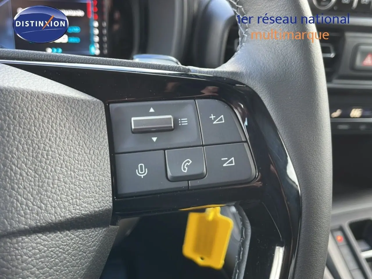 Gros plan sur les commandes au volant d’un Citroën Berlingo blanc glacier, avec boutons de volume et téléphone visibles.