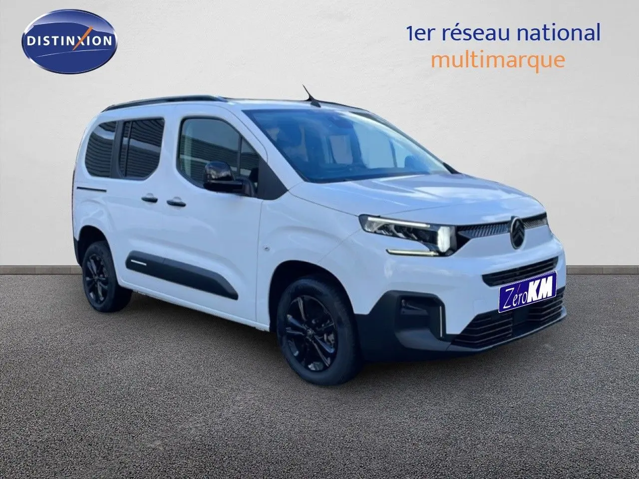 Vue 3/4 avant droit du Citroën Berlingo Multispace blanc glacier avec jantes noires et protections latérales noires.