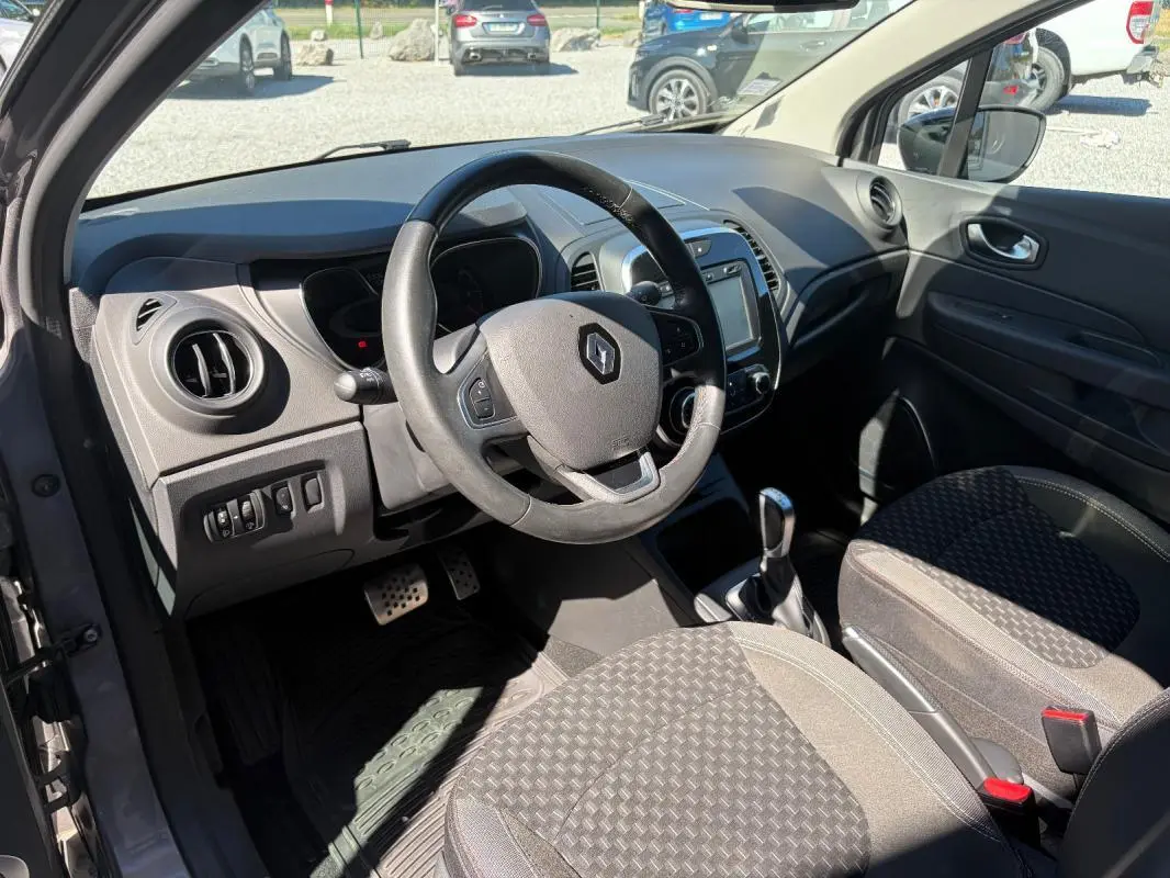Vue intérieure côté conducteur du Renault Captur gris 2017, volant multifonctions, écran tactile et levier de boîte auto visibles.