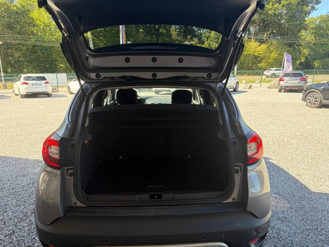 Vue arrière ouverte sur le coffre d'un Renault Captur gris 2017, montrant l'espace de chargement et les feux arrière.