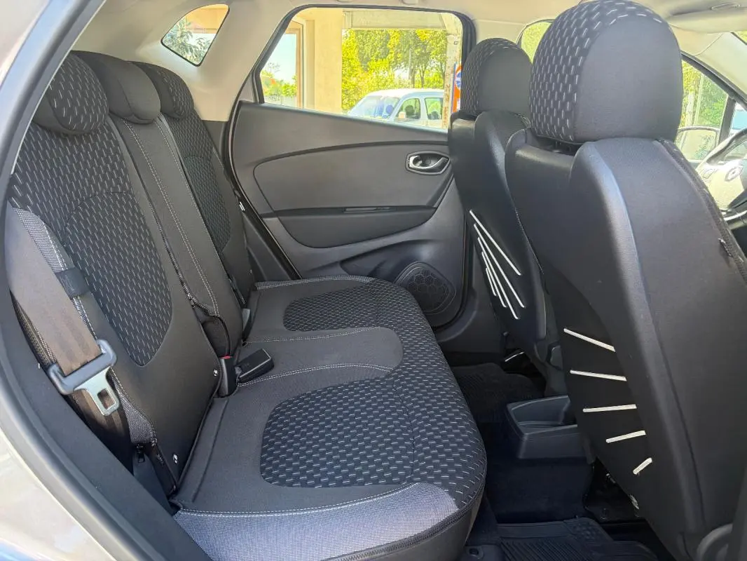 Vue intérieure côté gauche sur la banquette arrière noire du Renault Captur gris avec appuie-têtes et ceinture de sécurité visible.