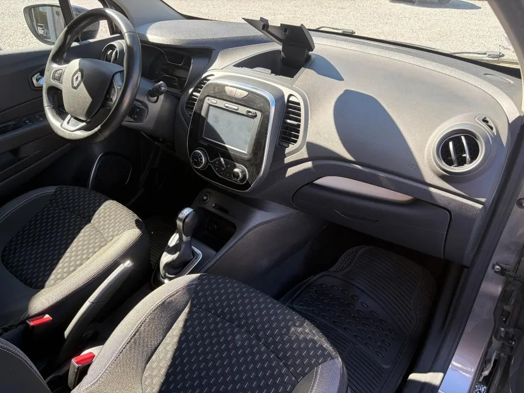 Vue intérieure côté conducteur du Renault Captur gris 2017, avec tableau de bord, écran GPS et volant multifonctions.