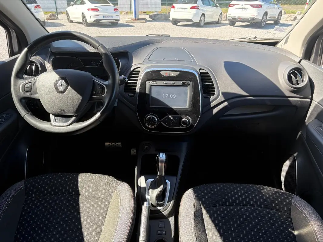 Vue intérieure avant du Renault Captur gris 2017, avec volant multifonctions, écran tactile et boîte automatique visible.